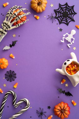 Cadılar Bayramı temalı dikey arka planda şeker mısır, balkabağı, iskelet ve mor bir yüzey üzerinde ürkütücü dekorasyonlar yer alıyor.