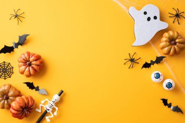 Balkabakları, ürkütücü yarasalar, korkunç örümcekler ve parlak turuncu arka planda bir hayaletin yer aldığı bayram düzenlemesi kutlama havası yaratıyor.