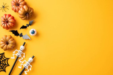 Balkabakları, iskeletler, yarasalar ve canlı turuncu bir zemin üzerinde bir örümceğin yer aldığı şenlikli Cadılar Bayramı arkaplanı