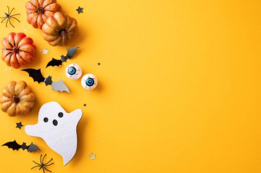 Cadılar Bayramı temalı arka planda balkabakları, yarasalar, bir hayalet ve turuncu bir yüzey üzerindeki ürkütücü dekorasyonlar yer alıyor.