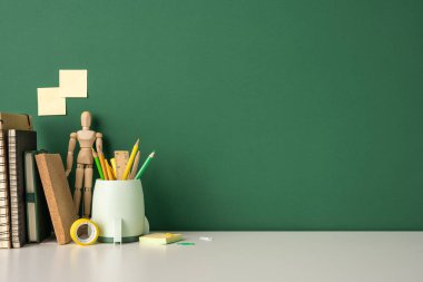 Masanın üzerinde kırtasiye malzemeleriyle okul konseptine geri dönelim. Defterler, kalemler ve ahşap bir manken.