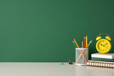 Çeşitli okul malzemelerinin ve masanın üzerinde sarı bir saatin olduğu okula dönüş konsepti.