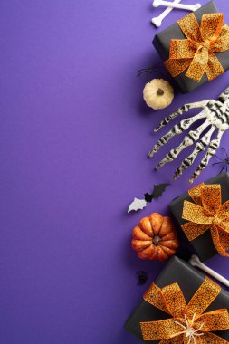 Cadılar Bayramı temalı dikey hediye kutuları turuncu yaylar, iskelet eller, mini balkabakları ve mor arka planda ürkütücü süslemeler.