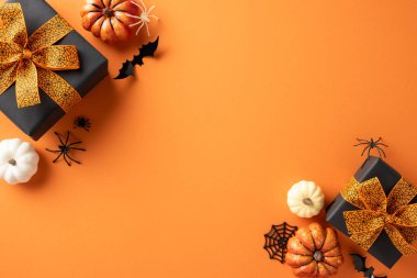 Cadılar Bayramı düzlük sahnesi, balkabakları, hediye kutuları, yarasalar ve turuncu arka planda örümcekler.