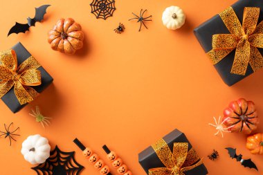 Cadılar Bayramı temalı balkabakları, yarasaları, örümcekleri ve turuncu arka plandaki süslemeleri içeren hediyeler neşeli bir atmosfer yaratıyor.