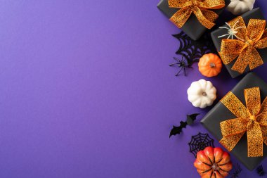 Mor arka planda turuncu kurdeleli, balkabaklı ve yarasalı Cadılar Bayramı hediye kutuları.