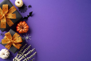 Cadılar Bayramı temalı hediyelerin üst görüntüsü turuncu yaylar, balkabakları ve mor arka planda ürkütücü süslemeler.