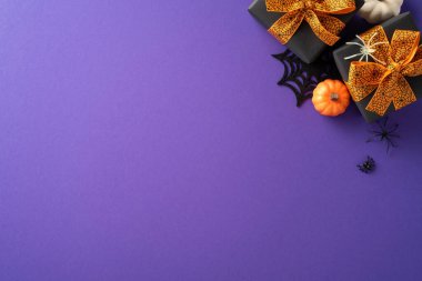 Cadılar Bayramı hediye kutuları turuncu yaylar, mini balkabakları ve mor arka planda örümcek süslemeleri. Şenlikli ve ürkütücü bir tatil dekoru.