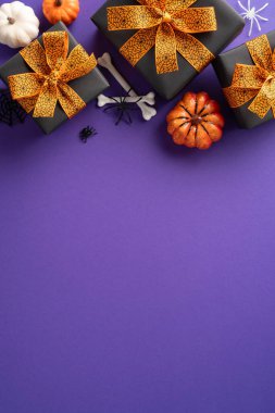 Cadılar Bayramı temalı dikey hediyeler turuncu kurdelelerle çevrili mor bir yüzey üzerindeki ürkütücü dekorasyonlarla