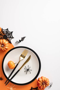 Küçük balkabakları, siyah ve altın çatal bıçak ve örümcek ve yarasa süslemeleri ile Cadılar Bayramı dikey masa ayarı