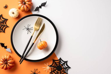 Cadılar Bayramı temalı masa düzeninde balkabakları, örümcek süslemeleri, siyah çatal bıçak takımı ve şenlik tabağı var.