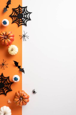 Portakal ve beyaz arka planda balkabakları, örümcek ağları, plastik gözler ve yarasalarla yaratıcı dikey cadılar bayramı düzeni. Cadılar Bayramı partileri, terfiler ya da mevsimlik selamlar için mükemmel.