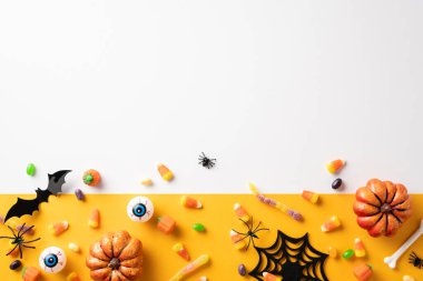 Cadılar Bayramı temalı resimde çeşitli şekerler, balkabakları ve canlı bir zemin üzerindeki örümcekler ve yarasalar gibi ürkütücü süslemeler var.