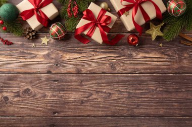 Güzel paketlenmiş Noel hediyeleri kırmızı kurdeleler ve sade ahşap arka planda düzenlenmiş şenlikli süslemeler sıcak bir tatil atmosferi yaratır.