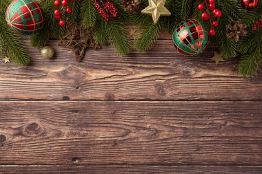 Kırsal ahşap arka planda renkli süsler ve yeşillik içeren şenlikli Noel süslemeleri. Mevsimlik kutlamalar ve bayram tebrik kartları için mükemmel.