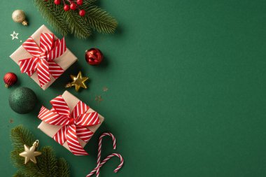 Kırmızı kurdele, şenlikli süsler ve yeşil arka planda çam dallarıyla güzelce paketlenmiş Noel hediyeleri neşeli bir tatil ortamı yaratıyor.