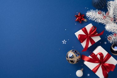 Kırmızı kurdeleli güzel Noel hediyelerinin ve mavi arka plandaki şenlikli süslemelerin manzarası neşeli bir tatil ortamı yaratıyor.