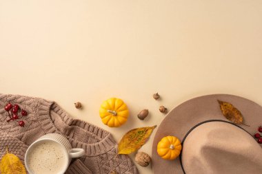 Sıcak bir süveter, sıcak kahve ve sonbahar yapraklı dekoratif balkabakları içeren şık bir sonbahar düzenlemesi mevsimlik sıcak bir hava yaratıyor.