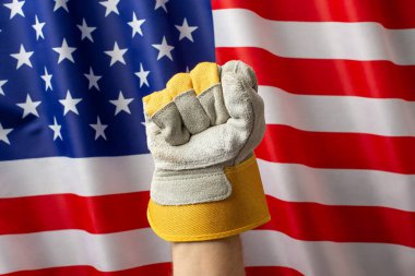 Amerikan bayrağının önündeki güçlü bir eldiven gururu, emeği ve birliği simgeler.