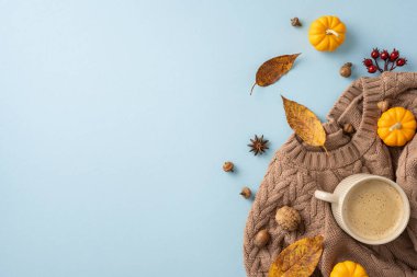 Ilık bir süveter, kahve, mini balkabağı, yapraklar ve mavi arka planda meşe palamudu içeren rahat bir sonbahar düzeninin düz uzantısı.