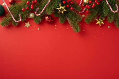 Çam dalları, baston şekerler ve altın yıldızların yer aldığı canlı kırmızı bir Noel arkaplanı, bayram neşesini ve şenlik ruhunu çağrıştırıyor.