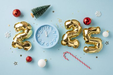 Bir saat, altın 2025 balon, süsler ve açık mavi arka planda bir şeker kamışı içeren şenlikli bir düzenleme.