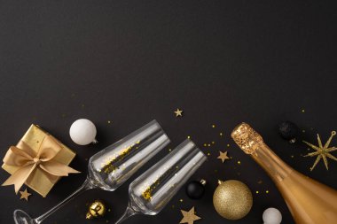 Şampanyayla, iki bardakla, bir hediye kutusuyla ve karanlık bir arka planda ışıltılı süslemelerle klas bir yeni yıl kutlaması.