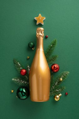 Noel süslemeleriyle çevrili dikey altın bir şampanya şişesi, çam dalları, takılar ve bir yıldız, yeşil bir arka plana dizilmiş, Noel ağacı yapıyor.