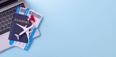 Bir pasaport, uçuş kartı ve oyuncak uçak bir dizüstü bilgisayarda seyahat hazırlığı ve tatil planlamasını gösteriyor.