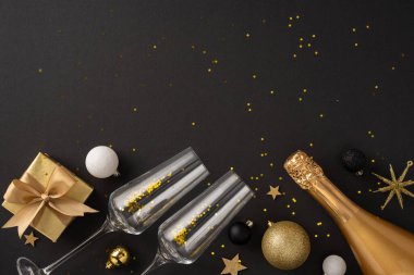 İki şampanya kadehi, bir altın şişe ve siyah arka planda dekoratif süslemelerle bir kutlama seti. Yeni yıl kutlamaları ve parti temaları için ideal.