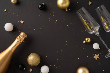 Şenlikli bir yeni yıl kutlamasının düz yatışı. Bir şampanya şişesi, iki bardak ve koyu bir arka planda altın süslemeler.