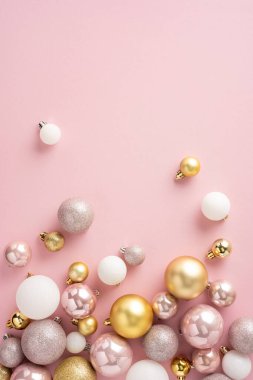 Yumuşak pembe bir arka planda gösterilen altın, beyaz ve pembe tonlarda zarif Noel süsleri dikey dizilimi neşeli ve neşeli bir atmosferi çağrıştırıyor.