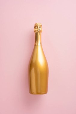 Pembe arka planda zarif, dikey, altın bir şampanya şişesi, kutlama ve lüksü simgeliyor. Yeni Yıl veya özel durum temaları için ideal