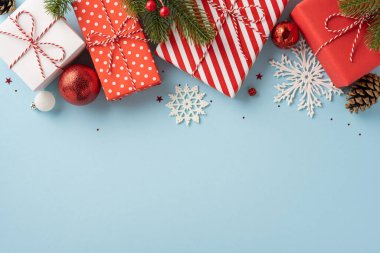 Renkli Noel hediyeleri ve pastel mavi arka planda kar taneleri olan süsler, neşeli ve neşeli tatil duygularını çağrıştırıyor.