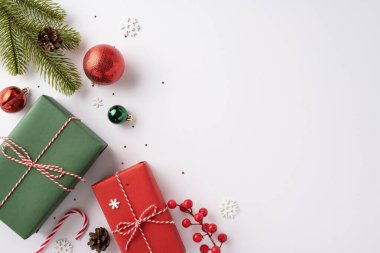 Kırmızı ve yeşil süslemeli güzel paketlenmiş Noel hediyeleri, köknar dalları ve hafif arka planda şenlikli dekorasyonlar.