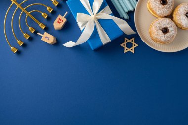 A Hanukkah celebration setup featuring a menorah, dreidels, gifts, and traditional donuts on a blue background. The elements evoke the festive and joyful spirit of the Hanukkah holiday clipart