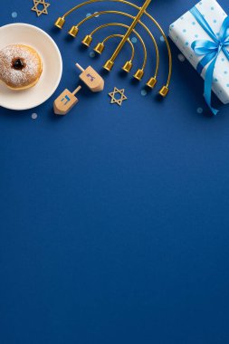 Menora, dreidels, Davut yıldızı, sufganiyah ve hediye kutusunun yer aldığı bayramlık bir Hanukkah sahnesi. Mavi tema, bayramın geleneksel unsurlarını ve neşeli ruhunu vurguluyor