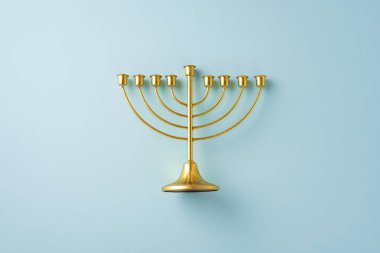 Pastel arka planda tertemiz minimalist bir tasarıma sahip güzel bir altın menora, Hanuka kutlamasını sembolize ediyor.