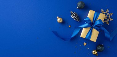 Mavi kurdeleli altın hediye kutusu mavi bir zemin üzerindeki şenlikli süslemelerle, zarafet ve tatil ruhunu iletiyor.