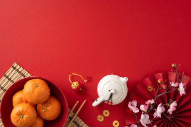 Portakallar, çaydanlık ve kırmızı arka planda çiçekler içeren, zenginliği ve kutlamaları sembolize eden Çin 'in yeni yıl unsurlarının düzlüğü.