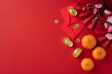 Kırmızı zarflar, altın paralar, portakallar ve kiraz çiçekleriyle dolu canlı bir Çin Yeni Yıl sahnesi refahı ve iyi talihi simgeliyor.
