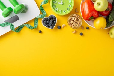 Sağlıklı gıda ve zindelik öğelerinin üst görüntüsü, dengeli bir yaşam tarzını destekleyen, canlı sarı bir arka planda.