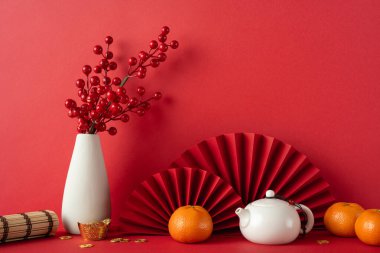 Çin Yeni Yılı 'nı canlı kırmızı madalyalarla kutlayın. Mandalinalar, çaydanlıklar ve çiçek düzenlemeleri refah ve mutluluğu sembolize ediyor.