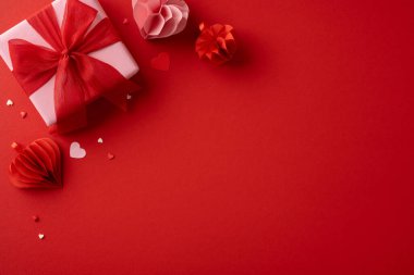 Romantik Sevgililer Günü hediyesi kırmızı bir kurdeleye sarılı kağıt kalpler ve küçük dekorasyonlar.