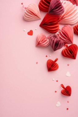 Pembe ve kırmızı kağıt kalplerden oluşan dikey bir koleksiyon. Sevgililer Günü kutlamaları ve romantik temalar için mükemmel. Sevgi ve sevgiyi ifade ediyor.