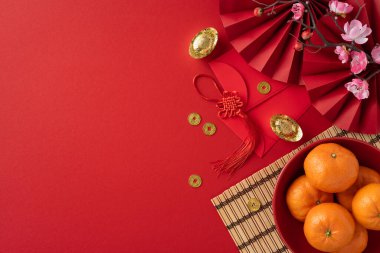 Kırmızı zarflar, altın paralar, portakallar ve canlı kırmızı arka planda çiçeklerin yer aldığı bir Çin Yeni Yılı festivali sahnesi. Gelenekleri ve kutlamaları iletmek için mükemmel.