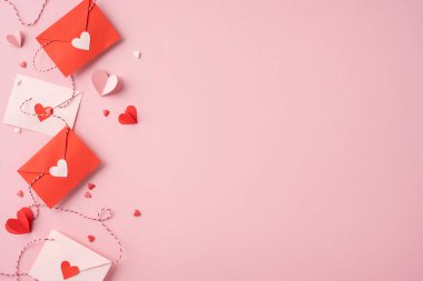 Pembe arka planda dizayn edilmiş kalp tasarımlı kırmızı ve beyaz zarflar. Sevgililer Günü temaları için mükemmel. Aşk ve romantizm aktarımı.