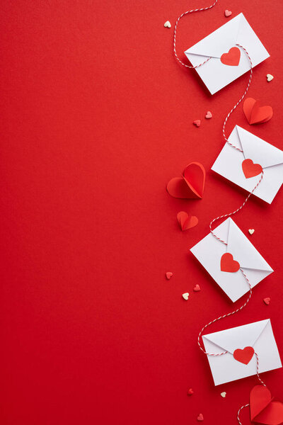 Вертикальная тема Дня Святого Валентина с конвертами и бумажными сердцами на ярком красном фоне, отражающая сущность любви и привязанности