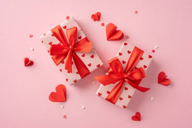 İki güzel paketlenmiş sevgililer günü hediyesi kırmızı kurdeleler ve pembe arka planda kalp süslemeleri, romantizmi ve sevgiyi temsil ediyor.