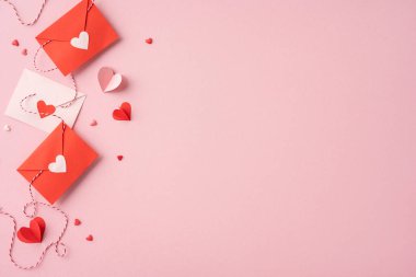 Pembe arka planda kalp süslemeleri olan kırmızı ve pembe zarflar, Sevgililer Günü için aşk ve romantizmi simgeliyor.